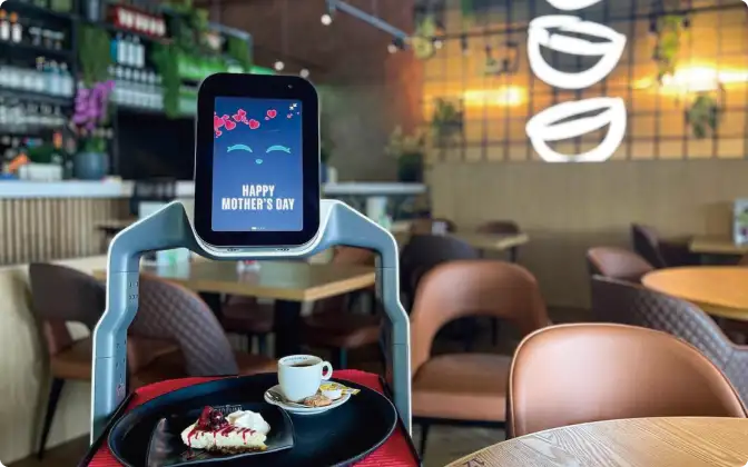 An OrionStar LuckiBot delivering a meal while displaying "Happy Mother's Day" on its screen.