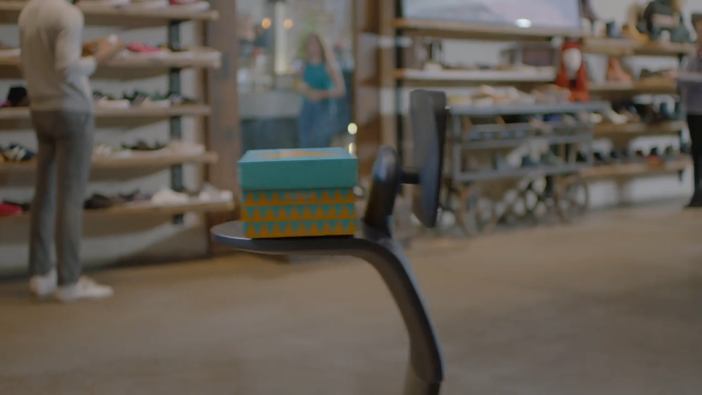 A temi robot delivering a shoe box on its platform.