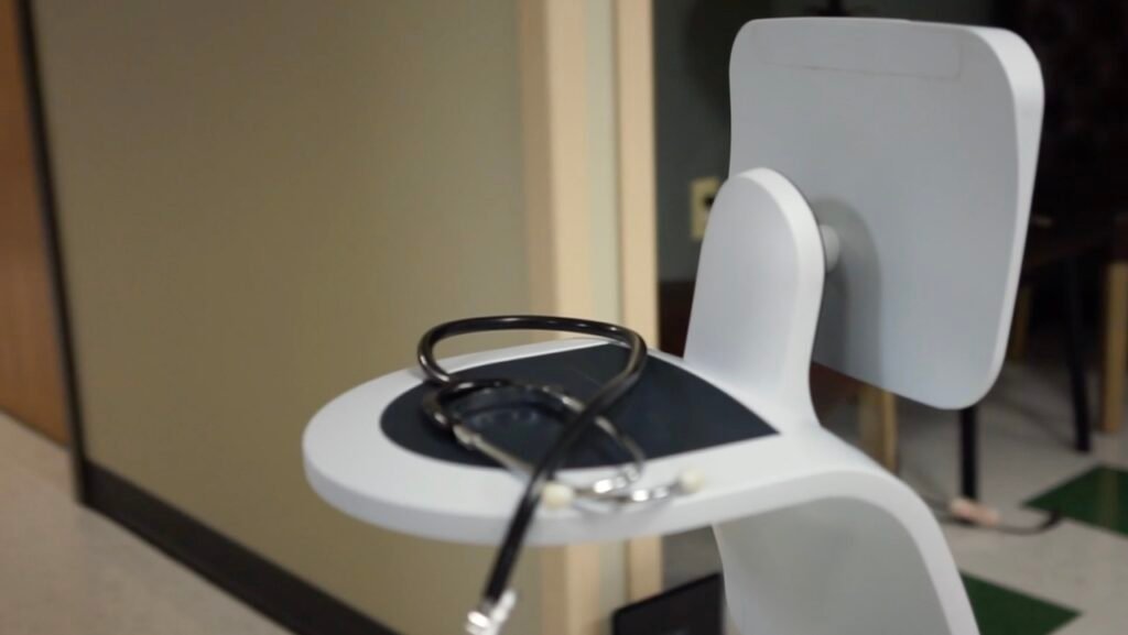 Stethoscope resting on a white clinical exam chair in a hallway.