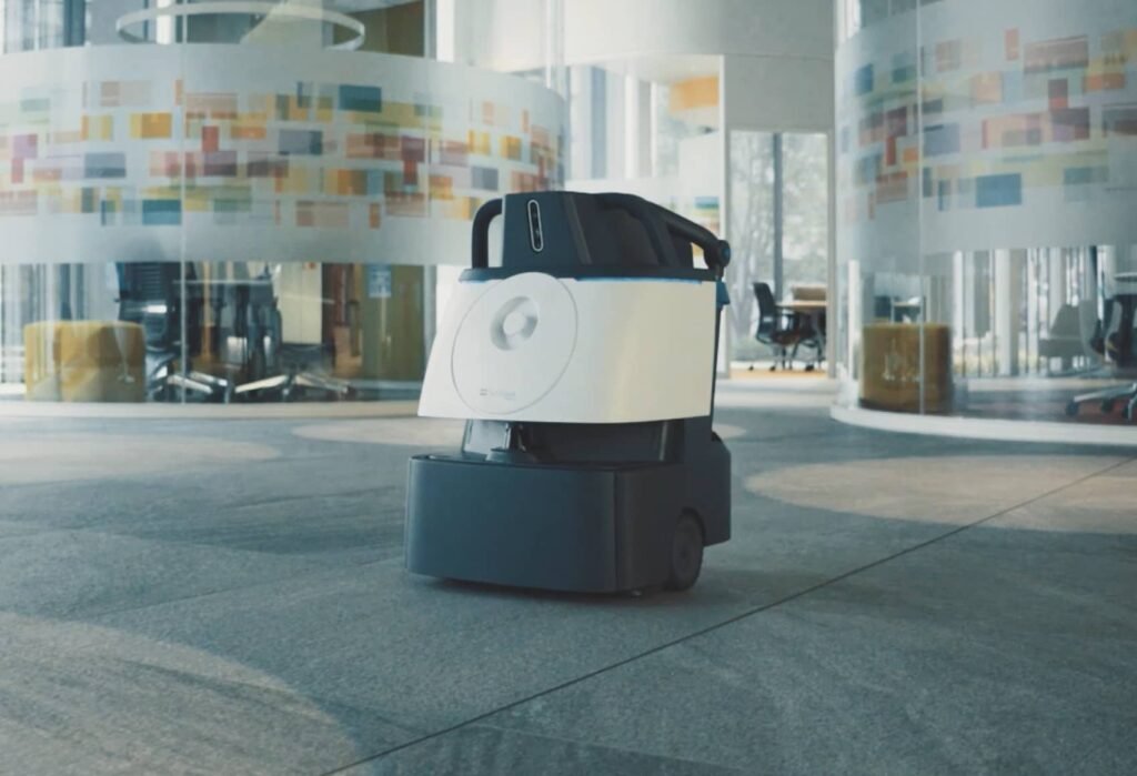 A Whiz cleaning robot in the middle of an office carpet.